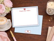 Load image into Gallery viewer, a table with a white card, a candle, a cup of coffee, and some flowers. The card has a blue and white checkered border and the name "Georgetina Wallace" written on it.